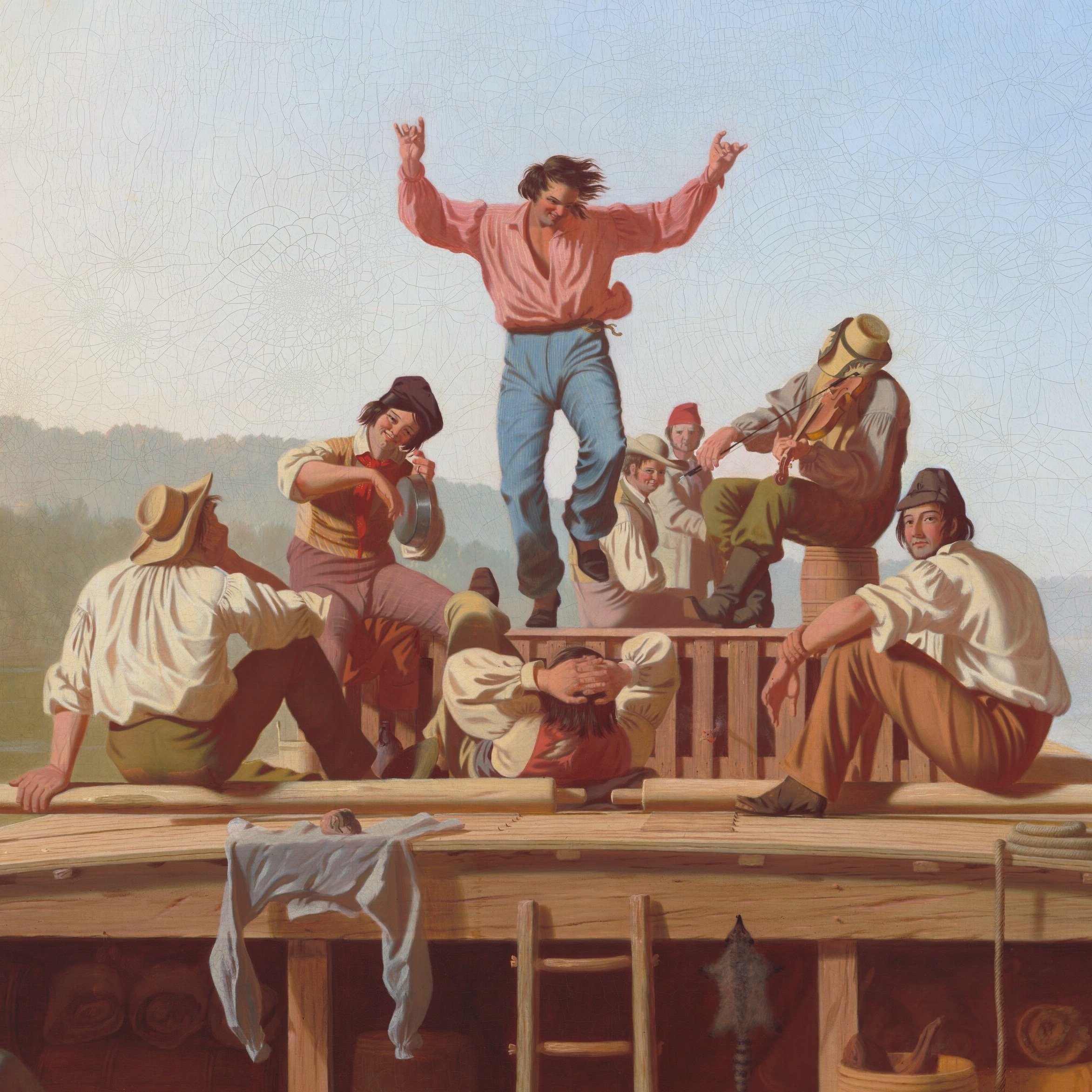 Group of people cheering as a man in a pink shirt stands on a platform with arms raised in victory.