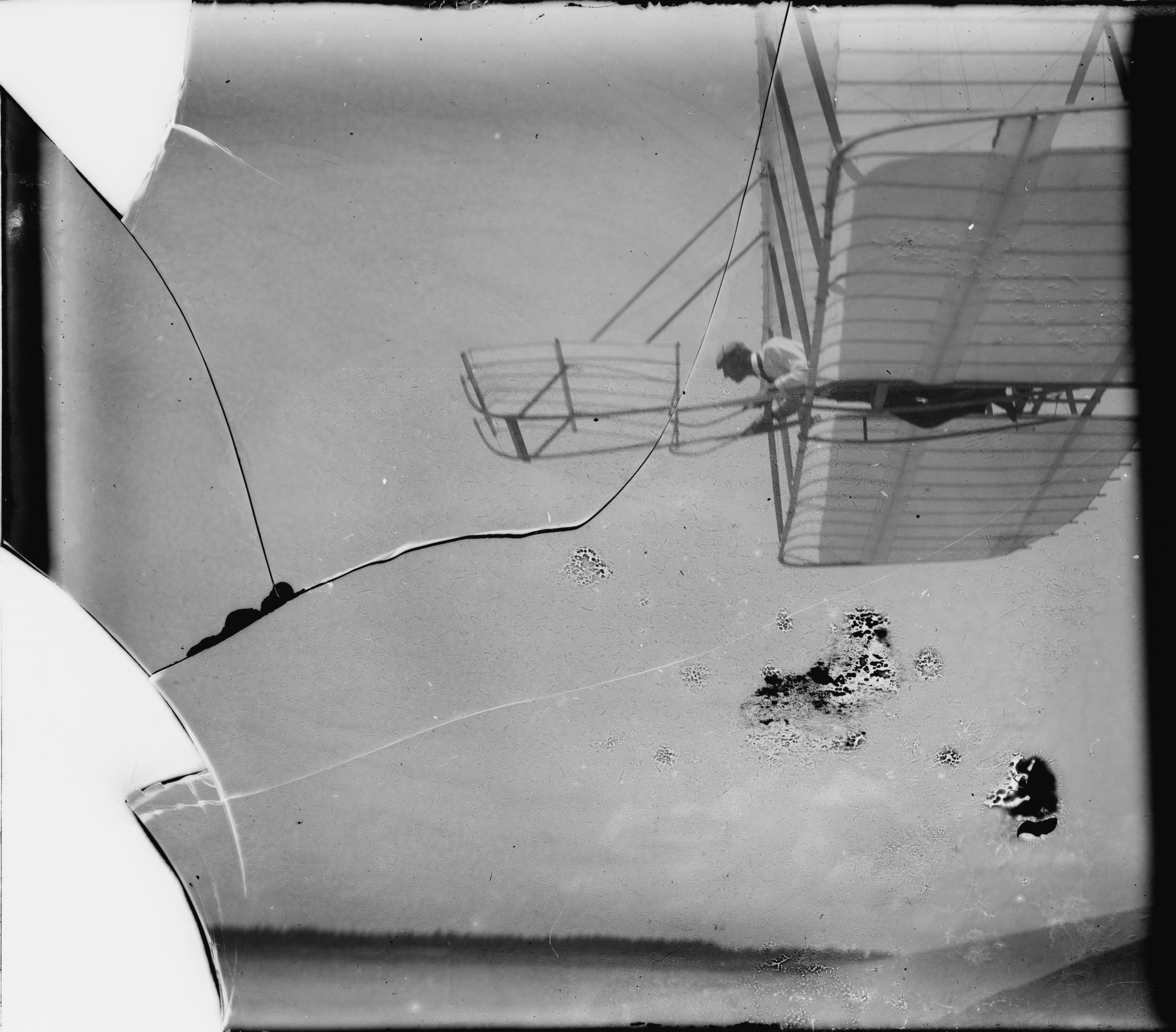 This is a Wright brothers photograph of Wilbur flying the 1901 glider. He is laying down at the controls as the glider passes over the head of the photographer.